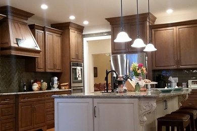 Exemple d'une cuisine chic en bois brun avec un plan de travail en granite, une crédence en carreau de verre, un électroménager en acier inoxydable et parquet clair.