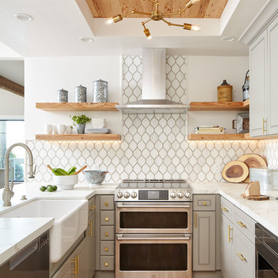 Beach style u-shaped light wood floor and beige floor kitchen photo in San Francisco with a farmhouse sink, recessed-panel cabinets, gray cabinets, white backsplash, stainless steel appliances, a peninsula, white countertops, marble countertops and ceramic backsplash