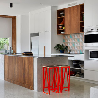Photo of a mid-sized scandinavian galley open plan kitchen in Melbourne with a double-bowl sink, white cabinets, quartz benchtops, cement tile splashback, stainless steel appliances, concrete floors, with island, grey floor and grey benchtop.