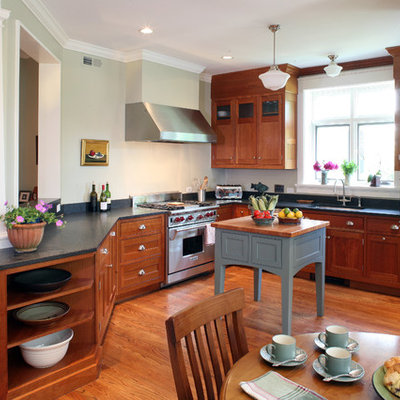 Mid-sized arts and crafts u-shaped light wood floor and red floor eat-in kitchen photo in DC Metro with shaker cabinets, medium tone wood cabinets, black backsplash, paneled appliances, a double-bowl sink, soapstone countertops and an island