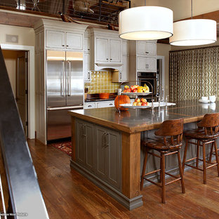 This is an example of a country eat-in kitchen in Other with a farmhouse sink, beaded inset cabinets, green cabinets, limestone benchtops, yellow splashback and stainless steel appliances.