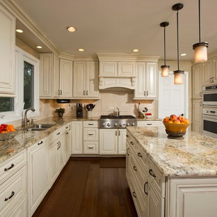 Large traditional u-shaped eat-in kitchen in DC Metro with a double-bowl sink, raised-panel cabinets, beige splashback, panelled appliances, granite benchtops, stone tile splashback, with island, beige cabinets and dark hardwood floors.
