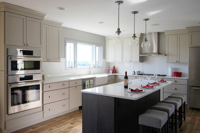 Inspiration for a medium sized traditional galley kitchen/diner in Cincinnati with a built-in sink, grey cabinets, white splashback, metro tiled splashback, stainless steel appliances, medium hardwood flooring and an island.