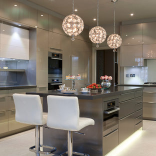 Imagen de cocina en U, contemporánea, grande, con armarios con paneles lisos, electrodomésticos de acero inoxidable, suelo de baldosas de cerámica, una isla, puertas de armario grises y salpicadero de vidrio templado