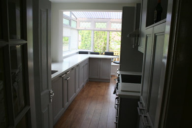 Inredning av ett modernt litet kök, med en undermonterad diskho, luckor med infälld panel, grå skåp, bänkskiva i koppar, vitt stänkskydd och mellanmörkt trägolv