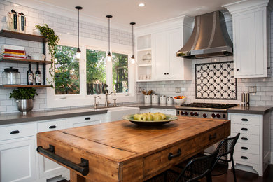 Enclosed kitchen - mid-sized eclectic u-shaped dark wood floor and brown floor enclosed kitchen idea in Los Angeles with a farmhouse sink, shaker cabinets, white cabinets, quartz countertops, white backsplash, subway tile backsplash, stainless steel appliances, an island and gray countertops