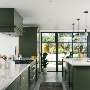 This is an example of a mid-sized transitional galley kitchen in Other with shaker cabinets, green cabinets, quartzite benchtops, white splashback, panelled appliances, with island, white benchtop, a farmhouse sink, concrete floors and grey floor.