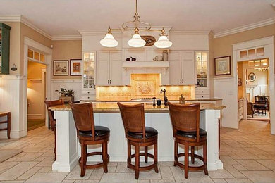 Inredning av ett klassiskt avskilt, mellanstort l-kök, med en undermonterad diskho, skåp i shakerstil, vita skåp, granitbänkskiva, beige stänkskydd, stänkskydd i keramik, rostfria vitvaror, kalkstensgolv, en köksö och beiget golv