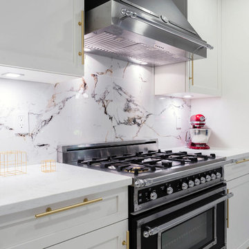 A kitchen with white shaker cabinets and Gold / Brass hardware and Bertazzoni ap