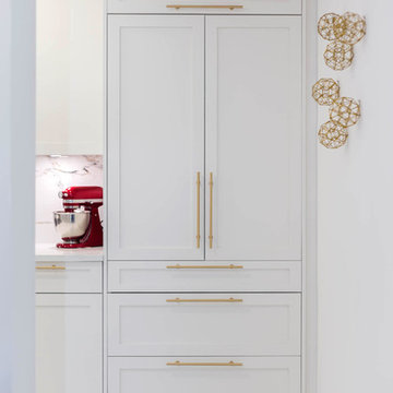 A kitchen with white shaker cabinets and Gold / Brass hardware