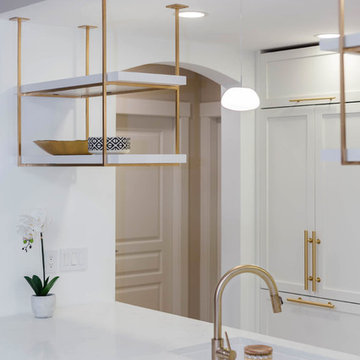 A kitchen with white shaker cabinets and Gold / Brass hardware