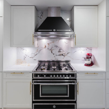 A kitchen with white shaker cabinets and Gold / Brass hardware with Berazzoni He