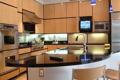 Ejemplo de cocina contemporánea con fregadero bajoencimera, armarios con paneles lisos, electrodomésticos de acero inoxidable, suelo de madera clara y con blanco y negro