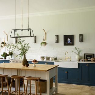 Traditional kitchen appliance - Elegant beige floor kitchen photo in Other with a farmhouse sink, shaker cabinets, blue cabinets, white backsplash, subway tile backsplash, an island and white countertops