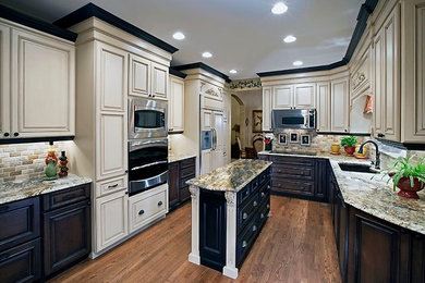 Enclosed kitchen - mid-sized traditional u-shaped medium tone wood floor and brown floor enclosed kitchen idea in Denver with an undermount sink, raised-panel cabinets, beige cabinets, granite countertops, beige backsplash, stone tile backsplash, paneled appliances, an island and beige countertops