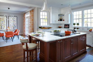 Large transitional l-shaped brown floor and dark wood floor eat-in kitchen photo in New York with white cabinets, marble countertops, white backsplash, ceramic backsplash, stainless steel appliances, an island, an undermount sink and raised-panel cabinets