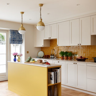 Zweizeilige Klassische Küche mit Unterbauwaschbecken, Schrankfronten im Shaker-Stil, weißen Schränken, Küchenrückwand in Orange, hellem Holzboden, Kücheninsel, beigem Boden und beiger Arbeitsplatte in London