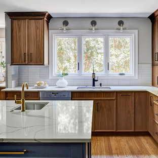 Inspiration for a large classic l-shaped open plan kitchen in Chicago with a submerged sink, medium wood cabinets, white splashback, medium hardwood flooring, an island, brown floors, flat-panel cabinets, engineered stone countertops, metro tiled splashback, stainless steel appliances and white worktops.
