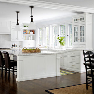 This is an example of a mid-sized traditional l-shaped eat-in kitchen in New York with recessed-panel cabinets, white cabinets, white splashback, subway tile splashback, stainless steel appliances, dark hardwood floors and with island.