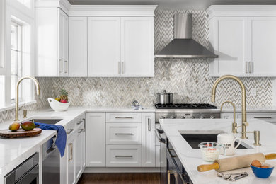 Enclosed kitchen - mid-sized transitional l-shaped brown floor and dark wood floor enclosed kitchen idea in New York with shaker cabinets, white cabinets, quartzite countertops, gray backsplash, marble backsplash, stainless steel appliances, an island, white countertops and an undermount sink