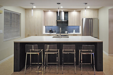 Mid-sized trendy u-shaped brown floor and porcelain tile eat-in kitchen photo in Miami with a single-bowl sink, flat-panel cabinets, quartz countertops, stainless steel appliances, an island, light wood cabinets, blue backsplash, subway tile backsplash and white countertops