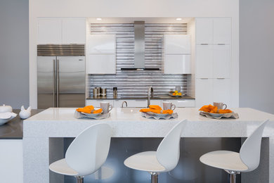 Inspiration for a mid-sized contemporary open concept kitchen remodel in Miami with flat-panel cabinets, white cabinets, metallic backsplash, matchstick tile backsplash, stainless steel appliances and an island