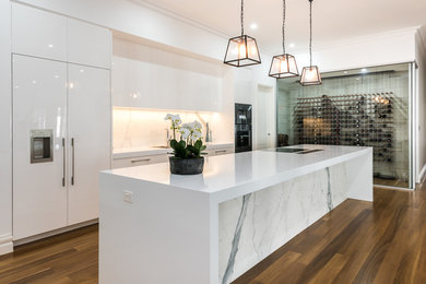 Foto di un cucina con isola centrale design di medie dimensioni con ante bianche, paraspruzzi bianco, paraspruzzi in gres porcellanato, pavimento in legno massello medio e top bianco
