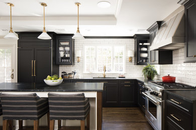 Exempel på ett stort klassiskt l-kök, med en undermonterad diskho, luckor med infälld panel, marmorbänkskiva, vitt stänkskydd, stänkskydd i tunnelbanekakel, rostfria vitvaror, mörkt trägolv, en köksö och brunt golv