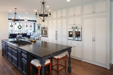 Example of a classic dark wood floor and brown floor open concept kitchen design in Denver with a single-bowl sink, beaded inset cabinets, white cabinets and an island