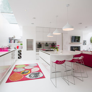 Cette photo montre une grand cuisine ouverte tendance en L avec un placard à porte plane, des portes de placard blanches, une crédence rose, un électroménager en acier inoxydable, un îlot central, un sol blanc, un évier encastré, un plan de travail en surface solide et une crédence en feuille de verre.