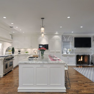 Photo of a large classic l-shaped open plan kitchen in New York with white cabinets, white splashback, integrated appliances, an island, recessed-panel cabinets, marble worktops, stone slab splashback, a submerged sink and dark hardwood flooring.