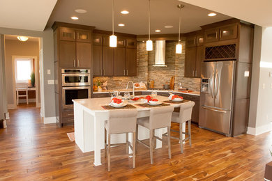 Mid-sized transitional kitchen photo in Milwaukee with an undermount sink, brown cabinets, stone slab backsplash, stainless steel appliances and two islands