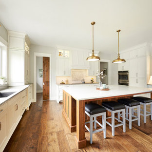 Transitional enclosed kitchen ideas - Transitional u-shaped medium tone wood floor enclosed kitchen photo in Other with an undermount sink, shaker cabinets, white cabinets, white backsplash, subway tile backsplash, stainless steel appliances, an island and gray countertops