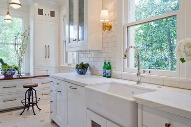 Enclosed kitchen - small traditional galley porcelain tile enclosed kitchen idea in Austin with a farmhouse sink, recessed-panel cabinets, white cabinets, marble countertops, white backsplash, subway tile backsplash, paneled appliances and no island