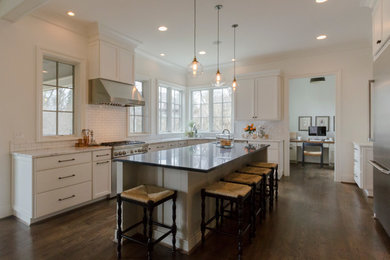 Inspiration for a large timeless galley dark wood floor eat-in kitchen remodel in Cincinnati with a farmhouse sink, shaker cabinets, white cabinets, white backsplash, subway tile backsplash, stainless steel appliances, an island and marble countertops