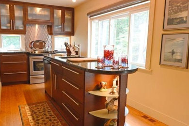 Example of a small 1950s bamboo floor kitchen design in Ottawa with an undermount sink, flat-panel cabinets, medium tone wood cabinets, granite countertops, metallic backsplash, stainless steel appliances and an island