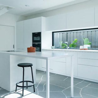 Photo of a mid-sized modern galley open plan kitchen in Perth with white cabinets, concrete benchtops and with island.