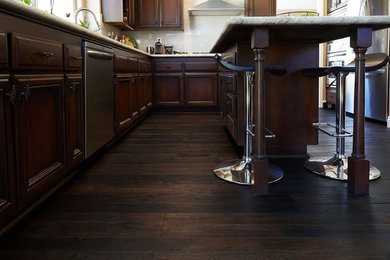 Inspiration for a large contemporary l-shaped dark wood floor and brown floor kitchen remodel in Sacramento with recessed-panel cabinets, dark wood cabinets, white backsplash, subway tile backsplash, stainless steel appliances and an island