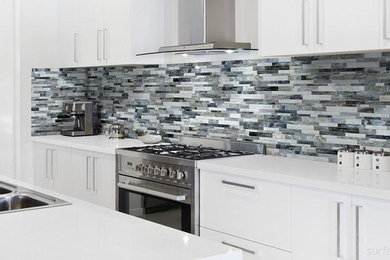 Moderne Küche mit Doppelwaschbecken, flächenbündigen Schrankfronten, weißen Schränken, bunter Rückwand, Rückwand aus Stäbchenfliesen, Küchengeräten aus Edelstahl und Kücheninsel in Sacramento