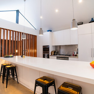 Design ideas for a large contemporary galley eat-in kitchen in Sydney with an integrated sink, white cabinets, metallic splashback, stainless steel appliances, concrete floors, with island, grey floor and white benchtop.