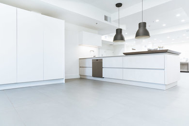 Diseño de cocinas en L contemporánea abierta con armarios con paneles lisos, puertas de armario blancas, encimera de laminado, electrodomésticos de acero inoxidable y península