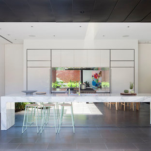 Inspiration for a contemporary galley kitchen in Melbourne with flat-panel cabinets, white cabinets, metallic splashback, mirror splashback, panelled appliances, with island, grey floor and white benchtop.