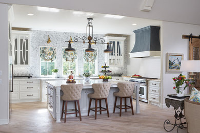 Kitchen - large traditional u-shaped light wood floor kitchen idea in Oklahoma City with raised-panel cabinets, white cabinets, gray backsplash, stainless steel appliances and an island