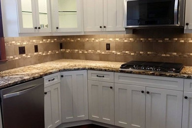 Inspiration for a mid-sized timeless l-shaped kitchen remodel in Seattle with shaker cabinets, white cabinets, granite countertops, beige backsplash, ceramic backsplash, stainless steel appliances and an undermount sink