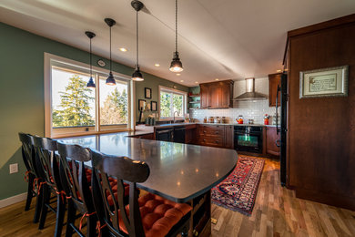 Example of a mid-sized u-shaped medium tone wood floor open concept kitchen design in Seattle with an integrated sink, beaded inset cabinets, dark wood cabinets, granite countertops, white backsplash, ceramic backsplash, black appliances and a peninsula
