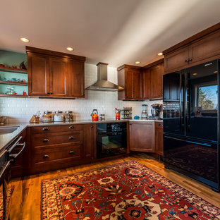 Inspiration for a mid-sized u-shaped open plan kitchen in Seattle with an integrated sink, beaded inset cabinets, dark wood cabinets, granite benchtops, white splashback, ceramic splashback, black appliances, medium hardwood floors and a peninsula.