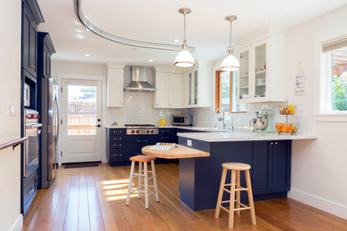 Inspiration for a large craftsman l-shaped light wood floor open concept kitchen remodel in San Francisco with a drop-in sink, recessed-panel cabinets, blue cabinets, quartz countertops, white backsplash, ceramic backsplash and stainless steel appliances