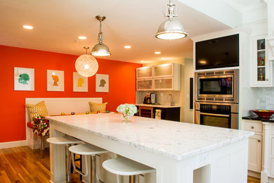Bild på ett stort lantligt kök, med en rustik diskho, luckor med profilerade fronter, vita skåp, bänkskiva i täljsten, grått stänkskydd, stänkskydd i stenkakel, rostfria vitvaror, ljust trägolv och en köksö