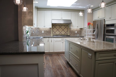 Inspiration for a medium sized traditional u-shaped kitchen/diner in San Francisco with raised-panel cabinets, white cabinets, engineered stone countertops, medium hardwood flooring, beige splashback, an island, a submerged sink, stainless steel appliances, mosaic tiled splashback, brown floors and beige worktops.