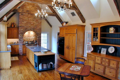 Example of a huge classic medium tone wood floor and brown floor kitchen design in New York with an undermount sink, recessed-panel cabinets, medium tone wood cabinets, wood countertops and paneled appliances